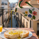 Aceitera de ceramica echando aceite de oliva virgen en una tostada tipo mollete en un balcon de andalucia